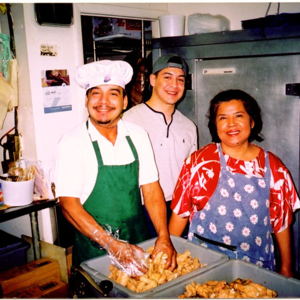 Three Pattaya Thai restaurant staff members smiling while preparing food in a kitchen.
