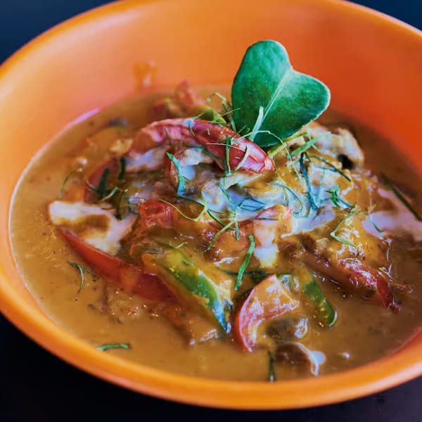 Pattaya Thai red curry with shrimp, bell peppers, and a kaffir lime leaf in an orange bowl.