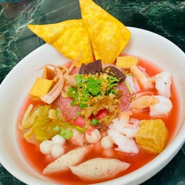 A vibrant bowl of Pattaya Thai's Yen Ta Fo noodles with seafood, tofu, and crispy wontons.