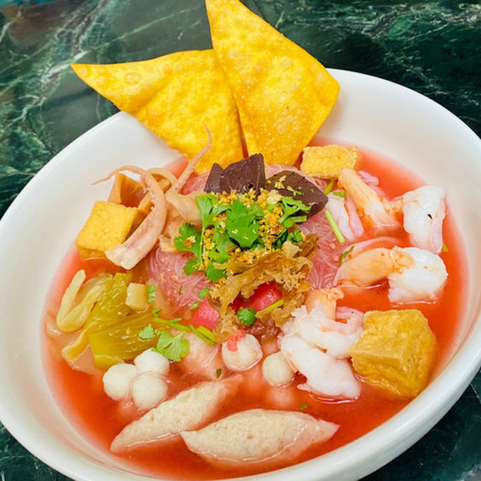 A vibrant bowl of Pattaya Thai's Yen Ta Fo noodles with seafood, tofu, and crispy wontons.